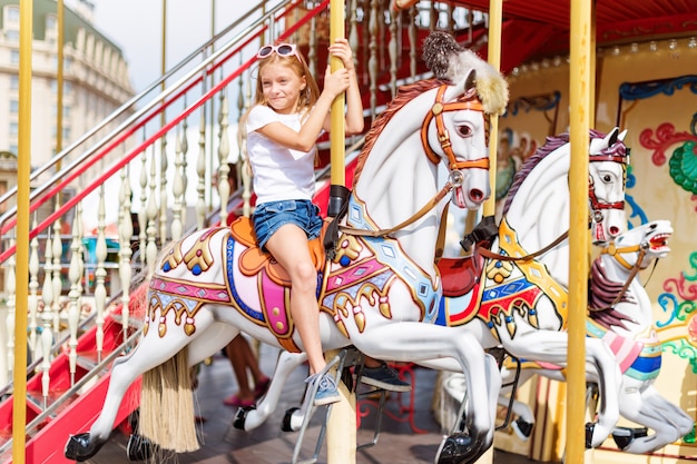 Meisje in een carrousel met paarden op een beurs