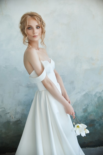 Meisje in een chique lange jurk zittend op de vloer. Witte trouwjurk