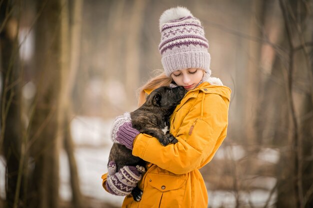 meisje in een geel jasje knuffelt een kleine puppy