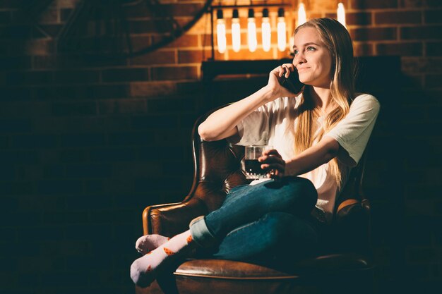 Meisje in een gezellige donkere kamer met een telefoon