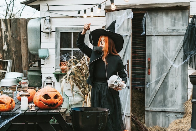 Foto meisje in een heksenkostuum op een halloweenfeest brouwt een drankje pot