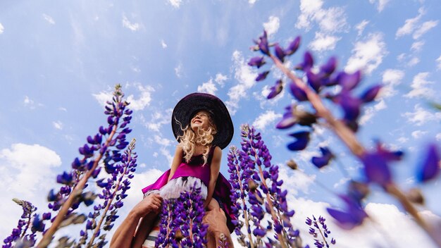 Meisje in een hoed op een achtergrond van lucht en lupine.