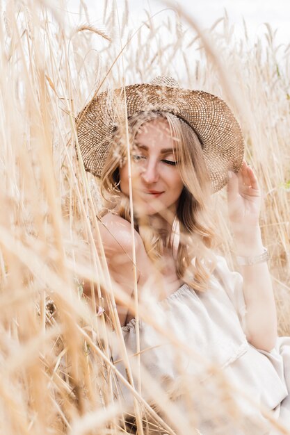 Meisje in een hoed op een tarwegebied in de zomer