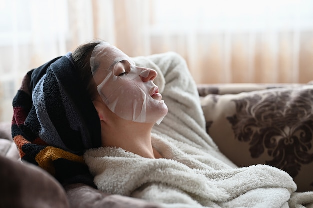 Meisje in een hydraterende gezichtsmasker ligt op een bank