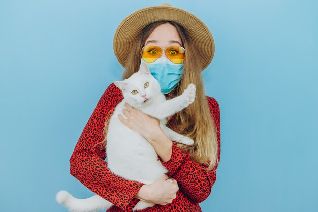 Meisje in een jurk, hoed en zonnebril met een medisch masker op haar gezicht. Vakanties in de epidemie van coronavirus.