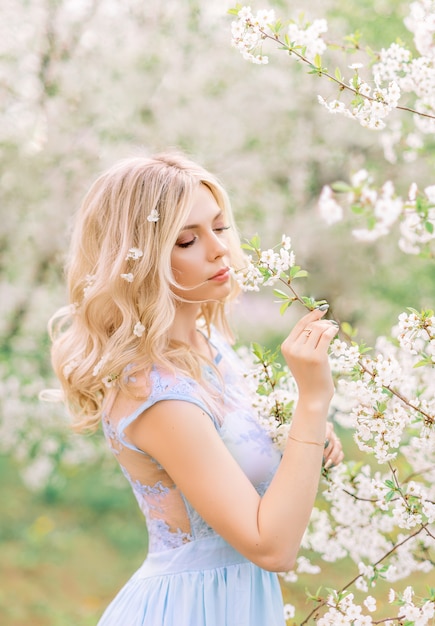 Meisje in een lentetuin die bloemen bewonderen. Portret in profiel. Bloemen in je haar