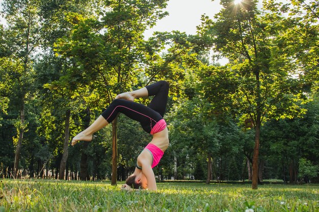 meisje in een licht trainingspak doet 's middags in de zomer yoga in het park