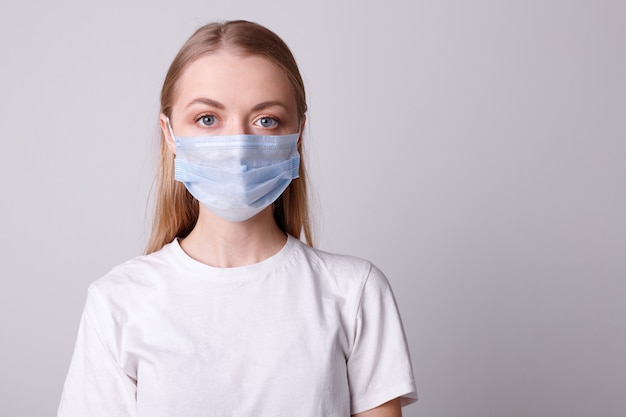 Meisje in een medisch masker op een grijze muur