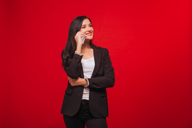 Meisje in een pak praten aan de telefoon. Op rode achtergrond