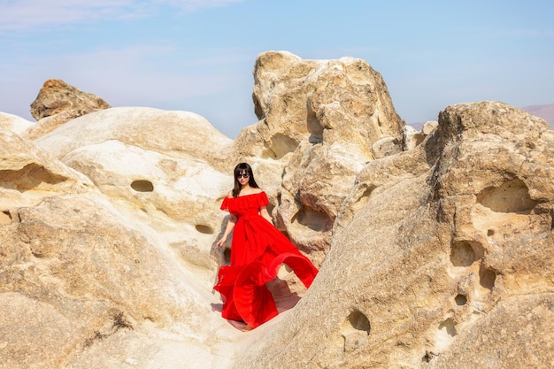 Meisje in een rode jurk in de buurt van de grotten in Cappadocië, Turkije