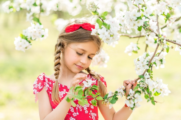 Meisje in een rode zomerjurk in een bloeiende tuin