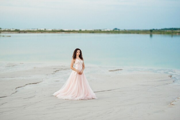 Meisje in een roze jurk loopt langs het witte zand van de woestijn