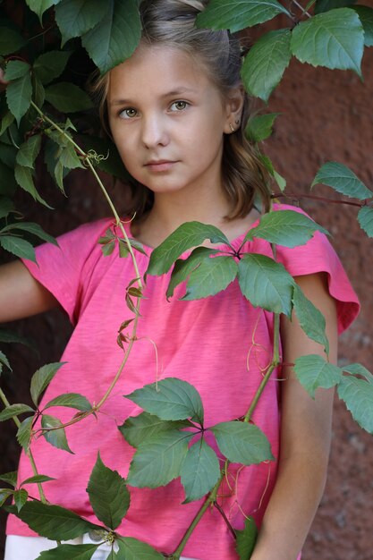 Meisje in een roze t-shirt in de bladeren van wilde druiven. close-up portret