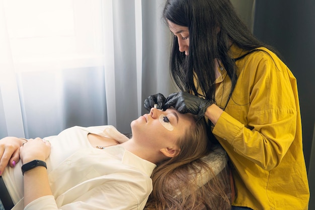 Meisje in een schoonheidssalon over de procedure om haar wimpers te kleuren, zorg voor wenkbrauwen en wimpers d...