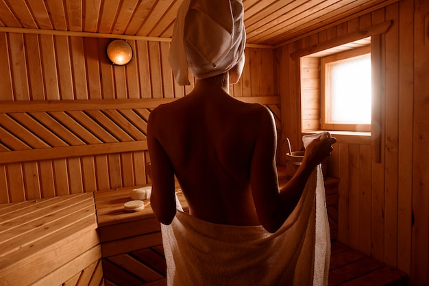 Foto meisje in een spa-behandeling in een traditionele sauna met een borstel voor de huid en een washandje.