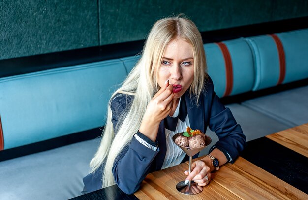 meisje in een streng pak in een café eet ijs