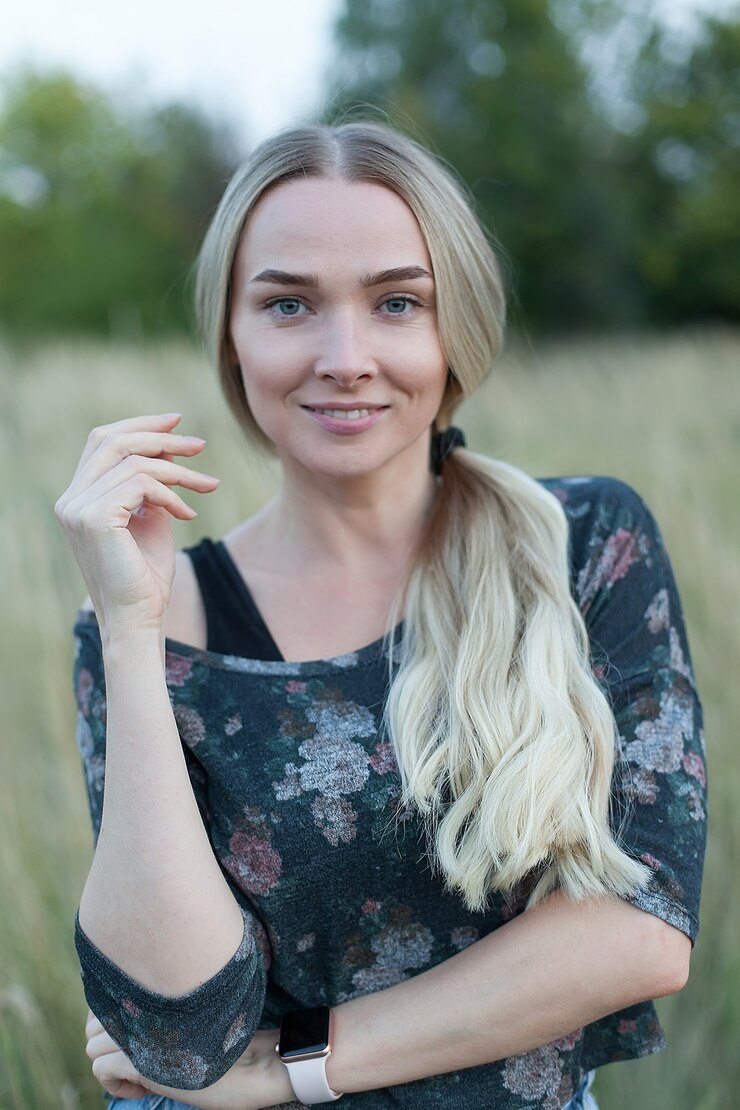 Foto meisje in een tarweveld. een jonge en mooie vrouw staat en kijkt naar de camera.