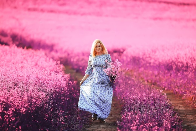 Meisje in een veld met lila bloemen in lavendelkleuren, violet en roze landschap, gelukkig en harmonie