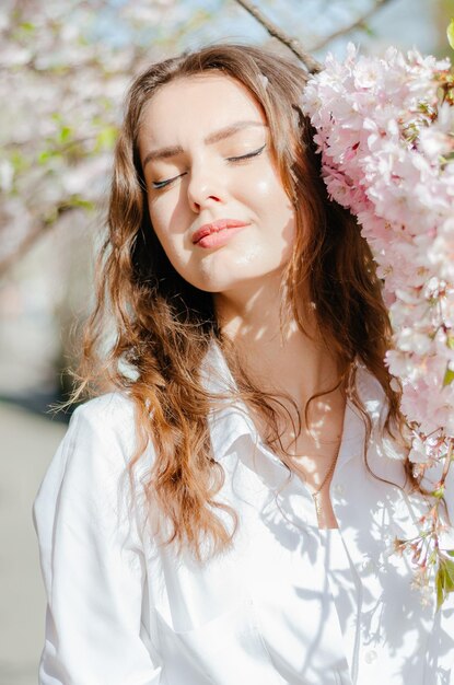 meisje in een wit overhemd staat in de buurt van de sakura