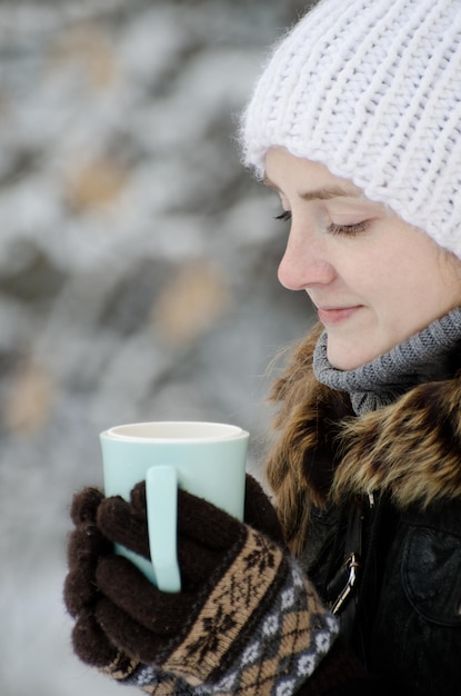 Meisje in een witte hoed in de winter met kopje thee zijaanzicht close-up