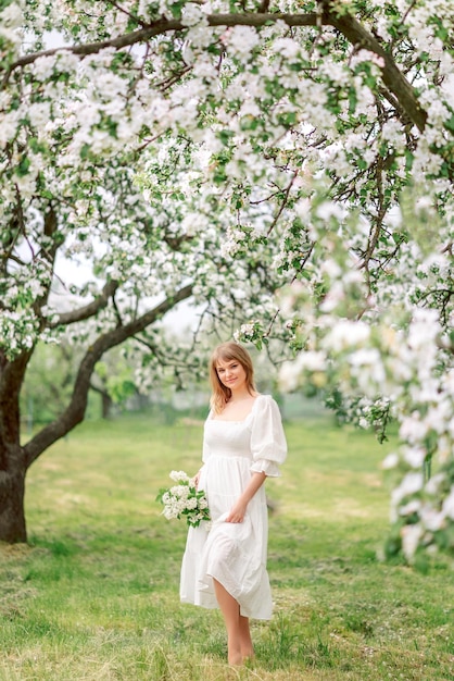 Meisje in een witte jurk loopt in de lente tuin.