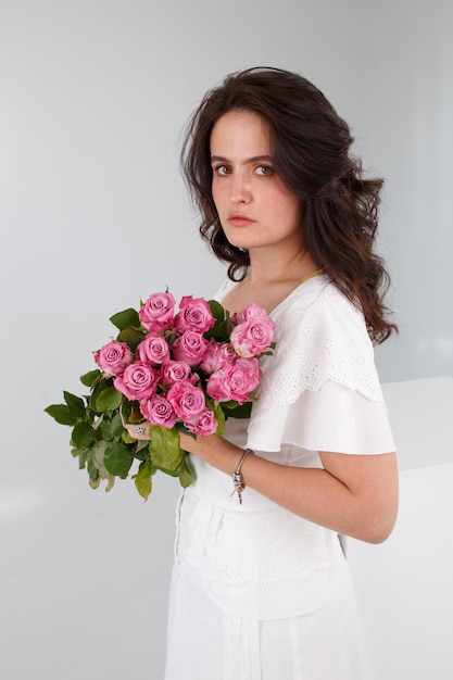 Meisje in een witte jurk met een boeket bloemen