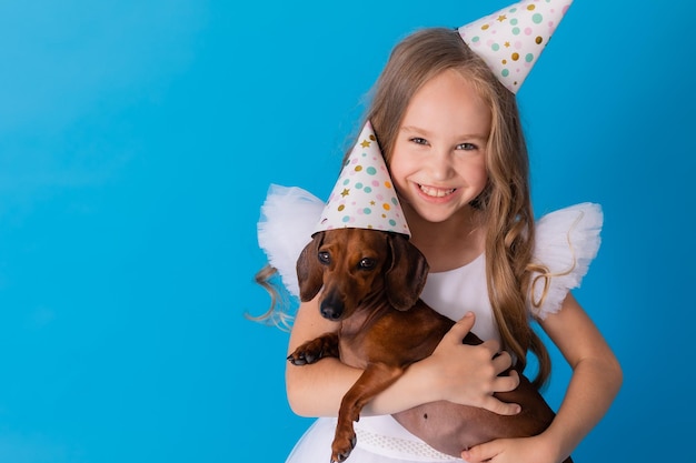 meisje in een witte pluizige elegante jurk met een teckelhond in haar armen