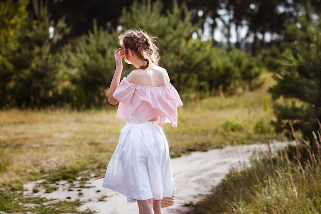 meisje in een witte rok wandelingen in de zomer. haar haar ontwikkelt de wind