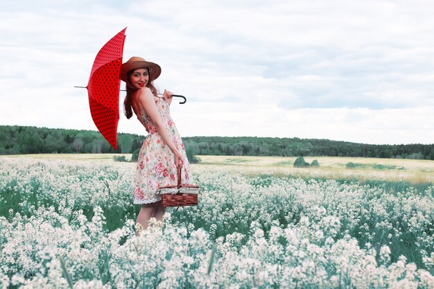 Meisje in een zomerweide met witte bloem in bewolkte dag