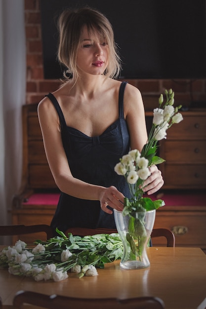 meisje in een zwarte jurk houdt witte rozen voordat ze in een vaas