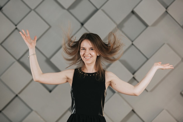 Foto meisje in een zwarte jurk speelt met haar haren en poses