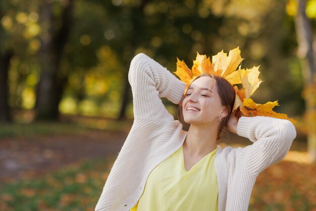 Meisje in gele kleren in het herfstpark verheugt zich in de herfst met gele bladeren in haar handen warm