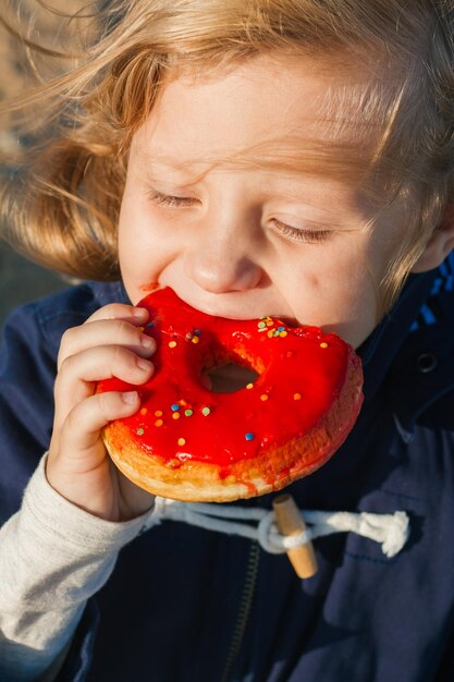 Foto meisje in genot eet donut met rood ijs voedsel vlekken haar mond