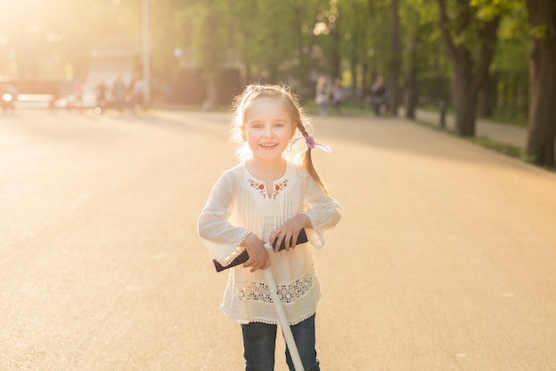 Meisje in het geborduurde shirt spelen met scooter