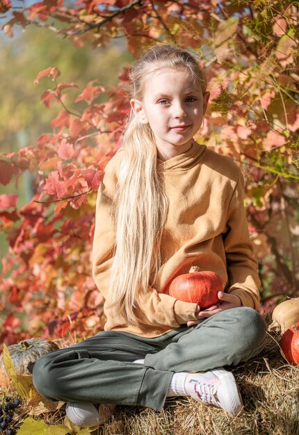 Meisje in het hooi met pompoenen