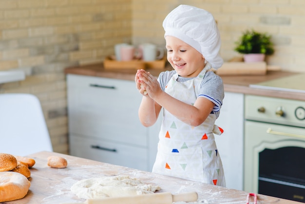 Meisje in het kostuum van een chef-kok het koken in de keuken