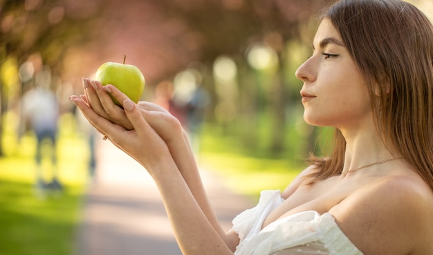 Meisje in het park met een appel in de hand