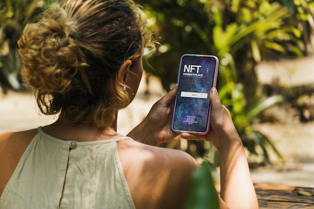 Meisje in het park met een smartphone met NFT NonFungible Token Marketplace-app op het scherm Rustieke houten tafel