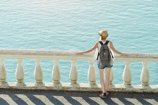 Meisje in hoed staande op het balkon en kijken naar de zee. Achteraanzicht