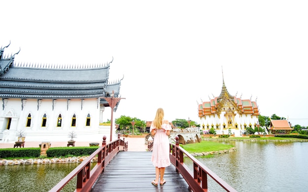 Meisje in jurk die een brug oversteekt voor de dusit maha prasat-troonzaal in thailand