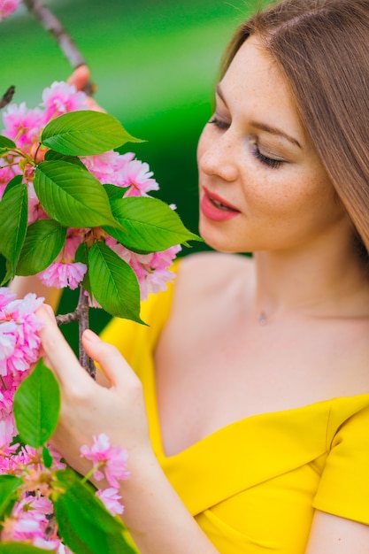 Meisje in jurk ruikende tak bloemen