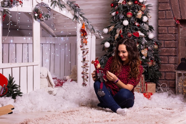 Meisje in Kerstmis Gelukkige vrolijke vrouw die het nieuwe jaar viert met geschenken in de buurt van de kerstboom