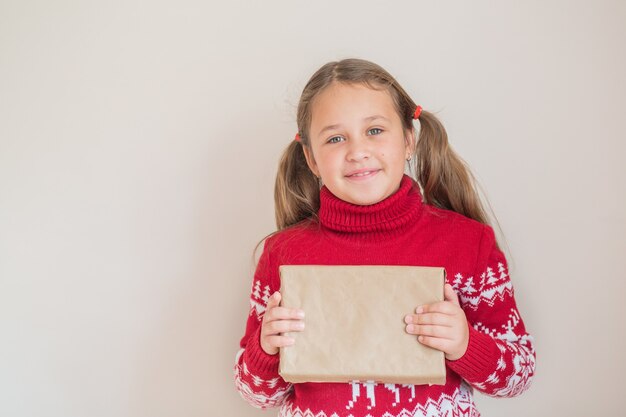 Meisje in Kerstmissweater met een gift