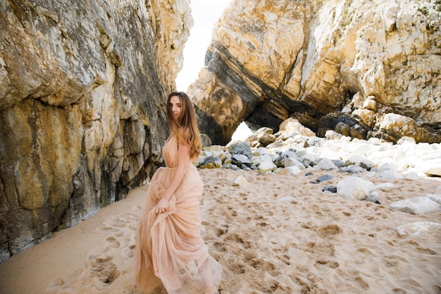 Meisje in lange jurk in de buurt van rotsen en oceaan