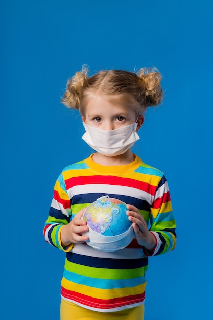 meisje in medisch masker met een wereldbol