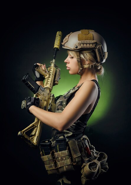 Meisje in militaire overall airsoft poseren met een pistool in haar handen