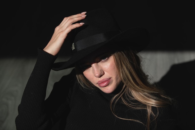 Meisje in mode hoed jonge vrouw poseren in studio over zwarte achtergrond licht en schaduw mode port