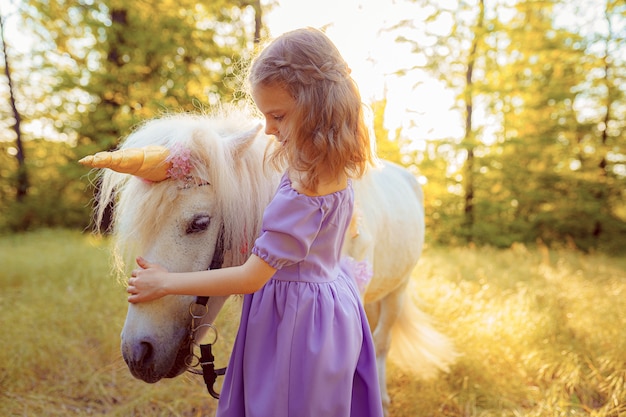 Meisje in paarse jurk knuffelen witte eenhoorn paard. Dromen komen uit. Sprookje