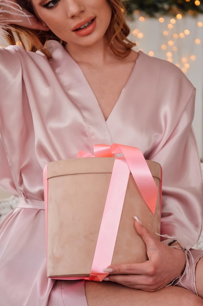 Meisje in pyjama in de ochtend opent een geschenk in een doos