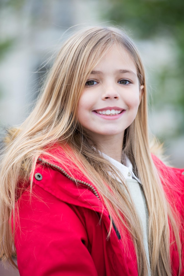 Foto meisje in rode jas zit op een bankje in het park.